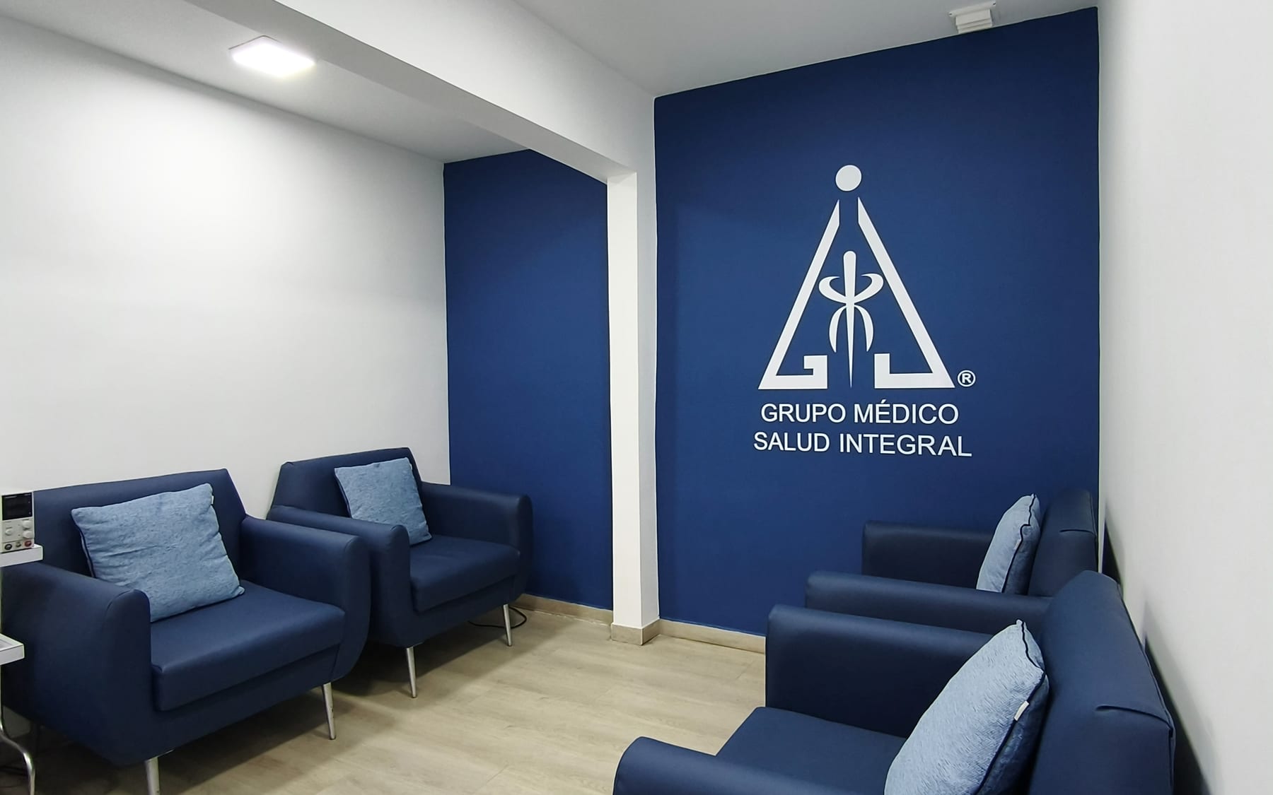 Área de terapias de MESAI: muro azul con el logo en blanco y sillones para tratamiento
